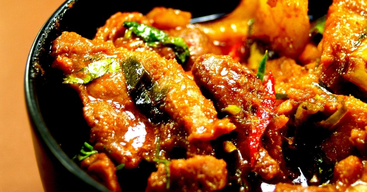 Prato de curry tailandês com pedaços de frango, vegetais e molho amarelo picante.