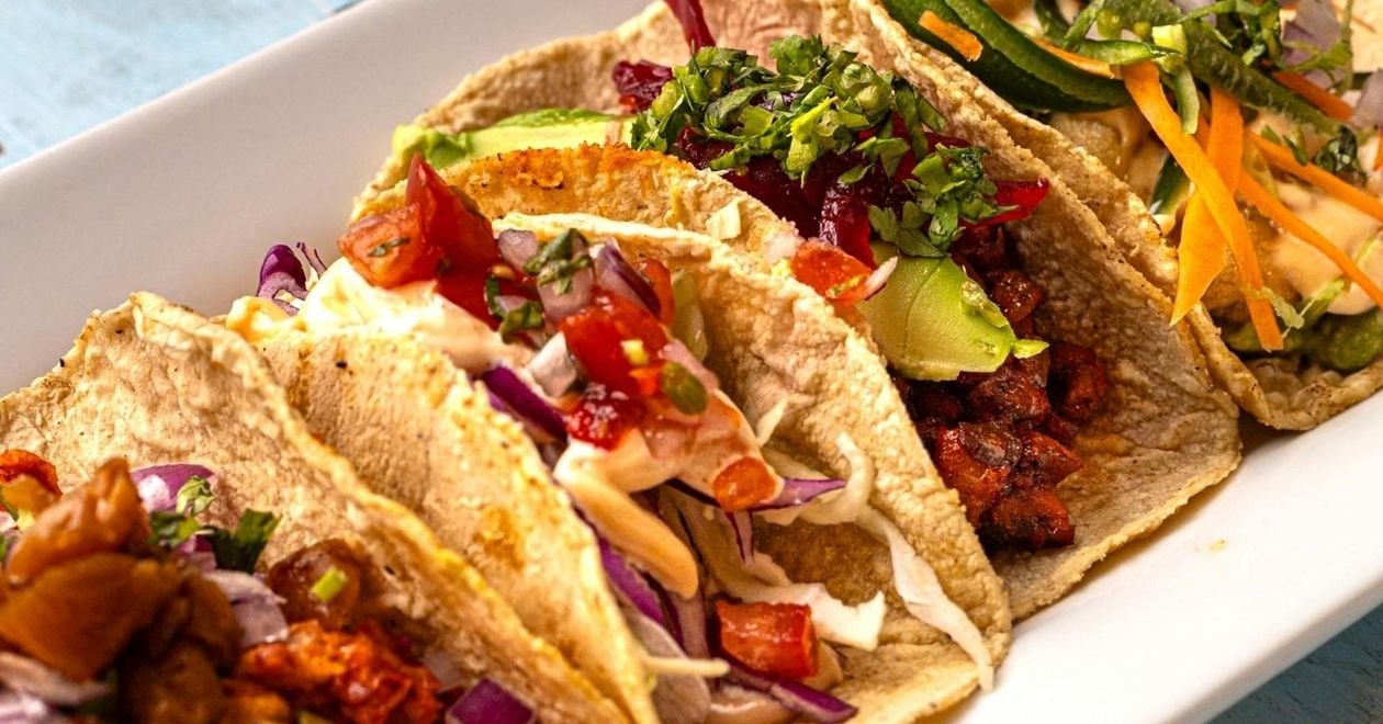 Tacos mexicanos, tortilhas de milho recheadas com carne, vegetais e molho.